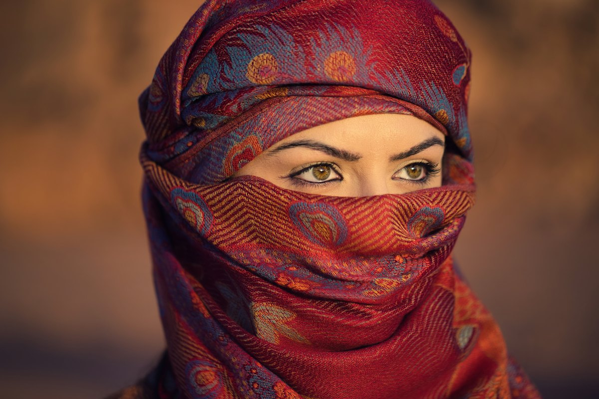 A woman with kohl-lined eyes and a red headscarf